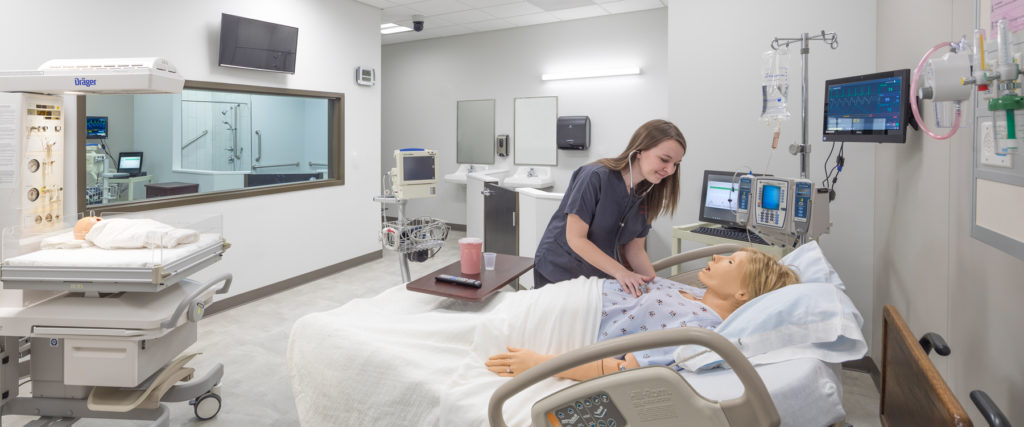 Young female nurse learning with a simulation dummy
